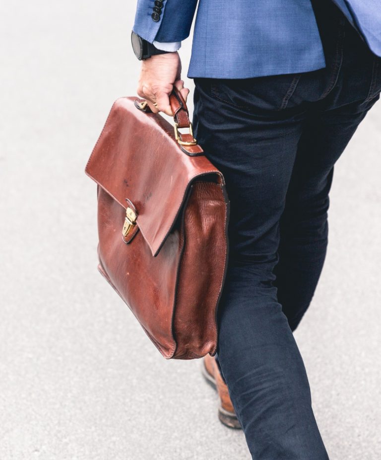 A man walking with a leather bag in his hand