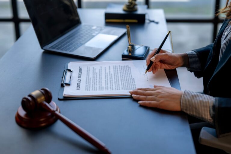 Legal professional signing court documents next to a gavel.